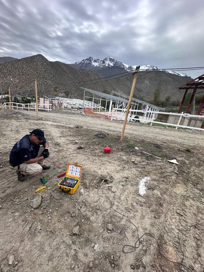 Técnico de CYS midiendo la resistencia de la malla de puesta a tierra con telurómetro y electrodos auxiliares tendidos, en una obra en Tulahuén