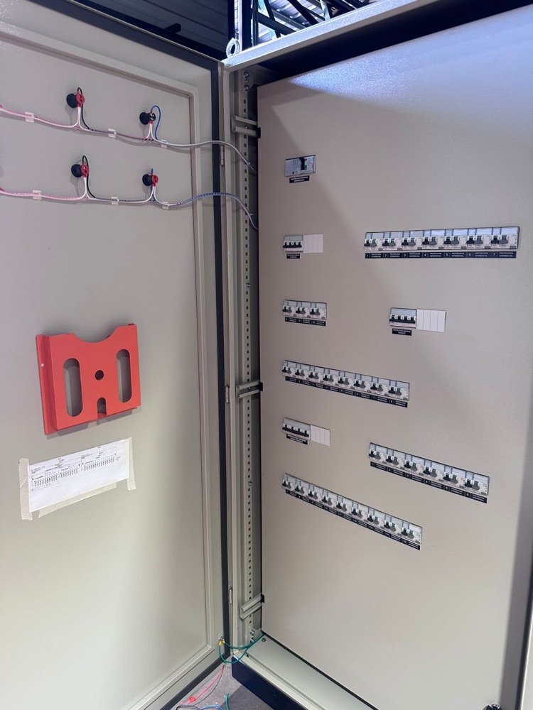 Tablero eléctrico de CYS con la puerta abierta: frente muerto con las protecciones rotuladas y el diagrama unilineal guardado dentro del tablero